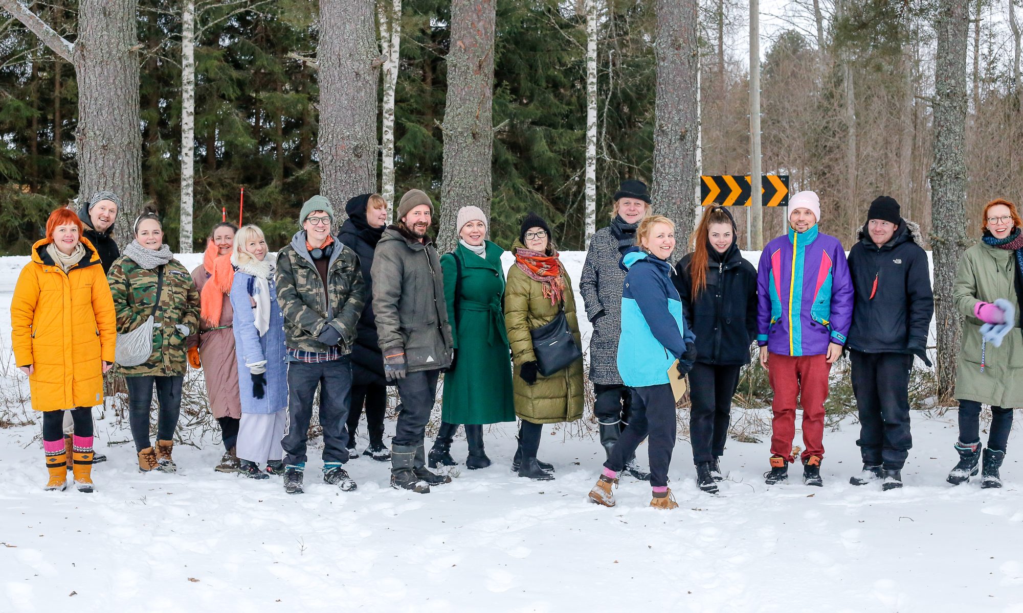 Haihatuksen kesänäyttelyn taiteilijat poseeraavat rivissä talvisessa maisemassa. Taustalla puita.